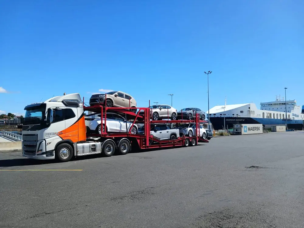 Beecheys Towing car carrier loaded with vehicles beside a ferry at a freight terminal