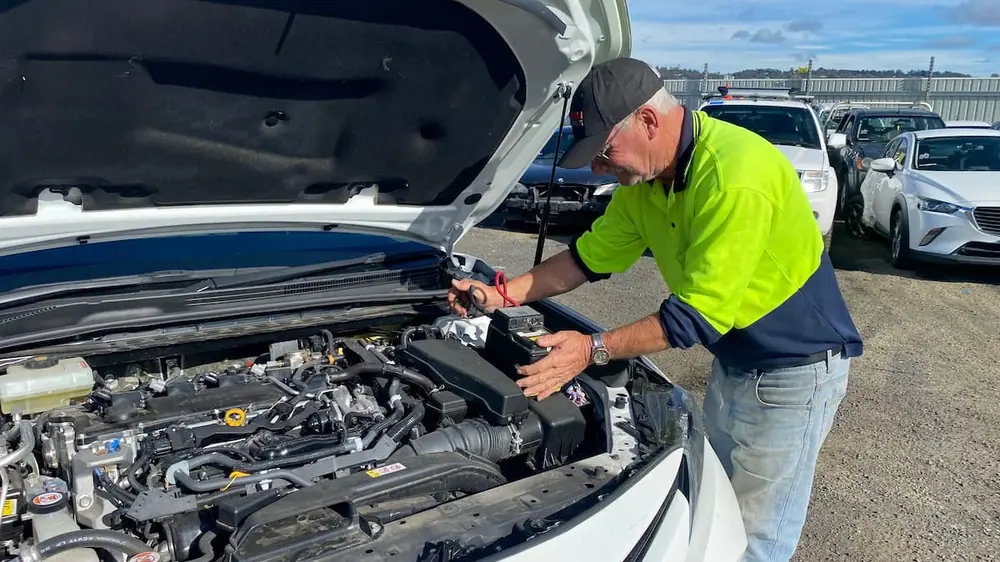 A Beecheys Towing crew member jump-starting a car battery roadside