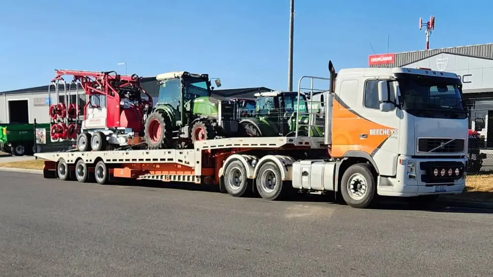 A Beecheys Towing truck hauling a tractor and farm implement on a low-loader